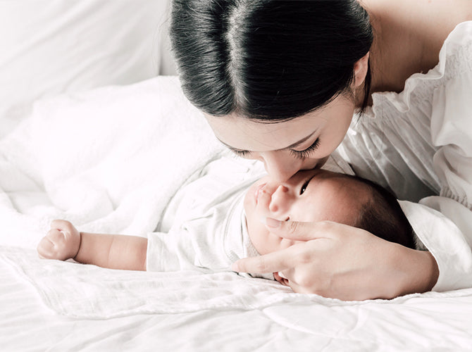 mom kissing newborn postpartum