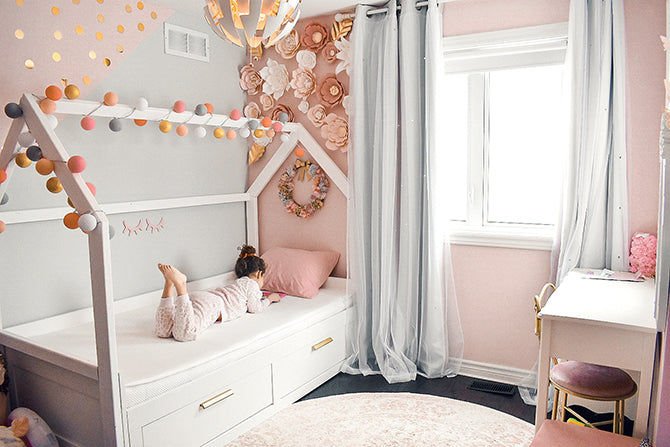 Kid laying and playing on a tablet on a toddler bed