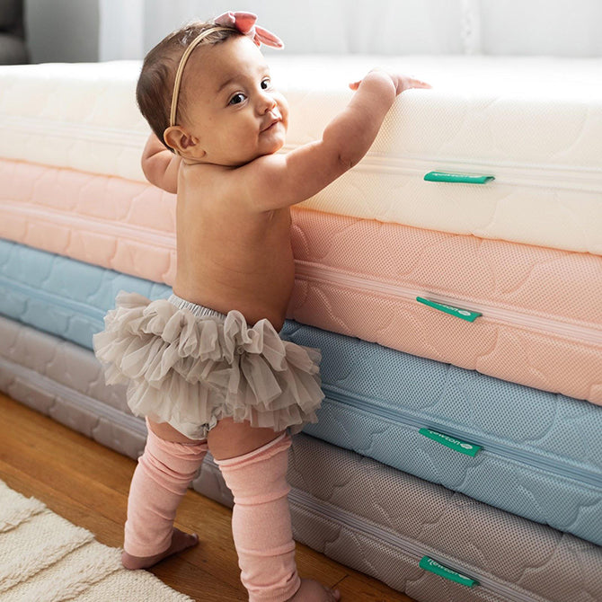 Baby standing near newton crib mattresses