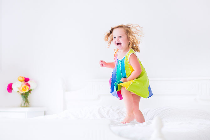 Young girl jumping on a bed