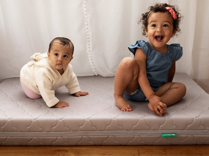 two toddlers sitting on a mattress