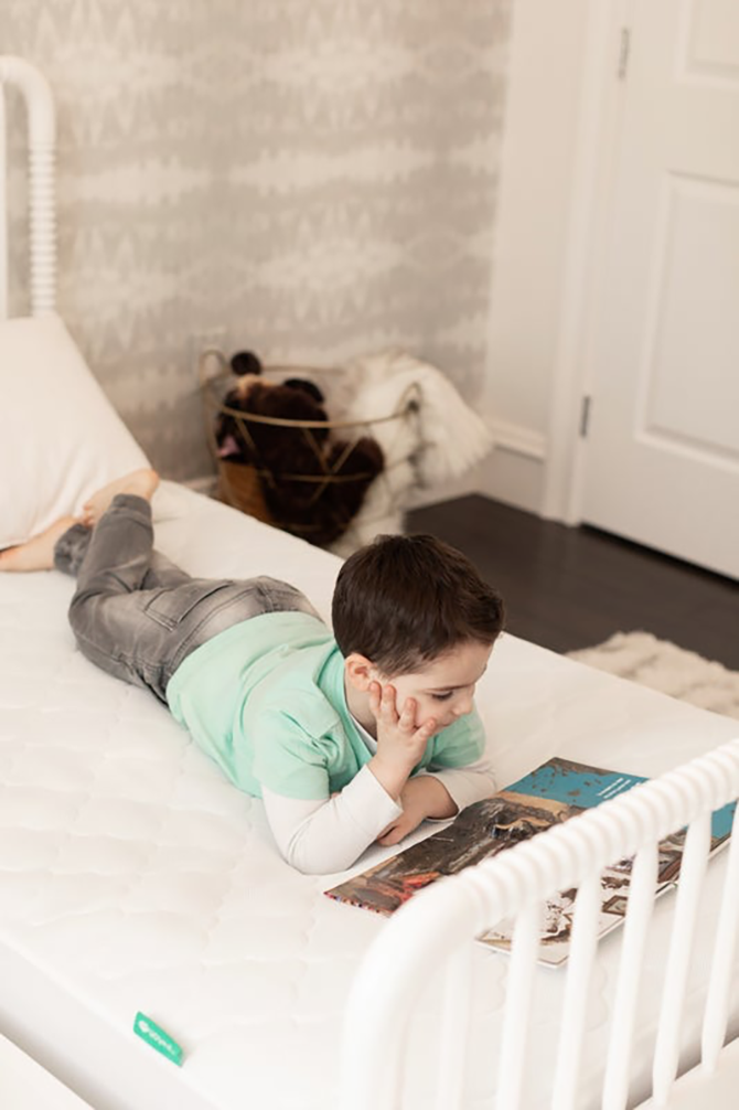 Young kid reading a book on his bed