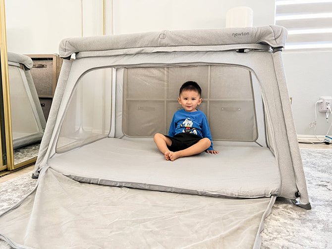 Toddler sitting in a travel crib