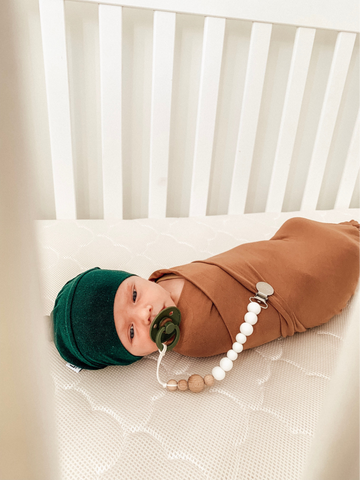 Baby swaddled with pacifier attached to the swaddle
