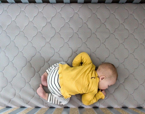 Baby laying in crib after parent learns when to stop swaddling