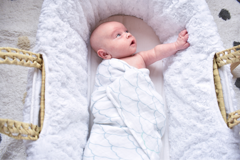 Baby with one arm out of swaddle letting parents know when to stop swaddling