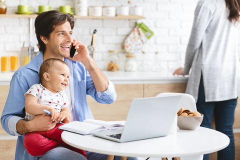 Dad holding baby while working from home with a baby