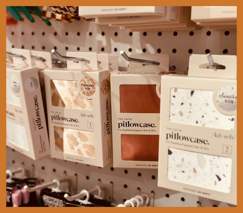A photo of Kitsch satin pillowcases in a variety of colors on our pegboard display in our Colchester, Vermont location.