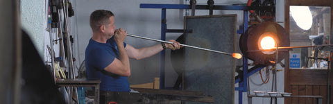 Rory Leadbetter - Master Glassblower at Jerpoint Glass blowing glass at his work station in the hot shop