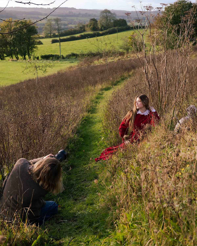 Haley sitting on hill wearing the red cord ash dress