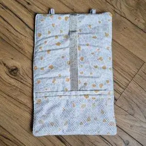 Pochette de rangement multi-usages en nid d'abeille à rouler et personnalisable. Cette pochette est complètement déroulée pour laisser voir les 4 poches et les 6 emplacements élastiques de différentes tailles permettant d'y ranger câbles, chargeurs, produits de beauté, brosse à dent, etc. L'intérieur de cette pochette est doublée d'un tissu imprimé à motif Argeo et peut se tenir enroulée grâce à deux petits élastiques.