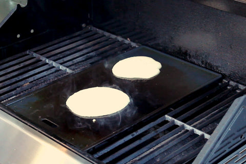 Pfannkuchen-Teig auf einer heißen Grill-Platte, die auf einem Gasgrill liegt.