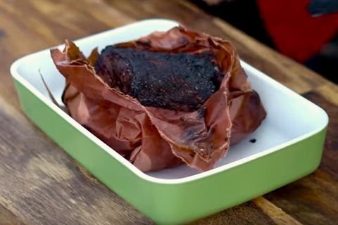 Nachdem das Fleisch fertig gegrillt ist, liegt es mit bereits aufgerissenem Butcherpaper in einer Schale.