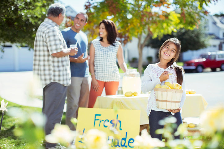 Portrait of smiling girl holding lemons at lemonade stand