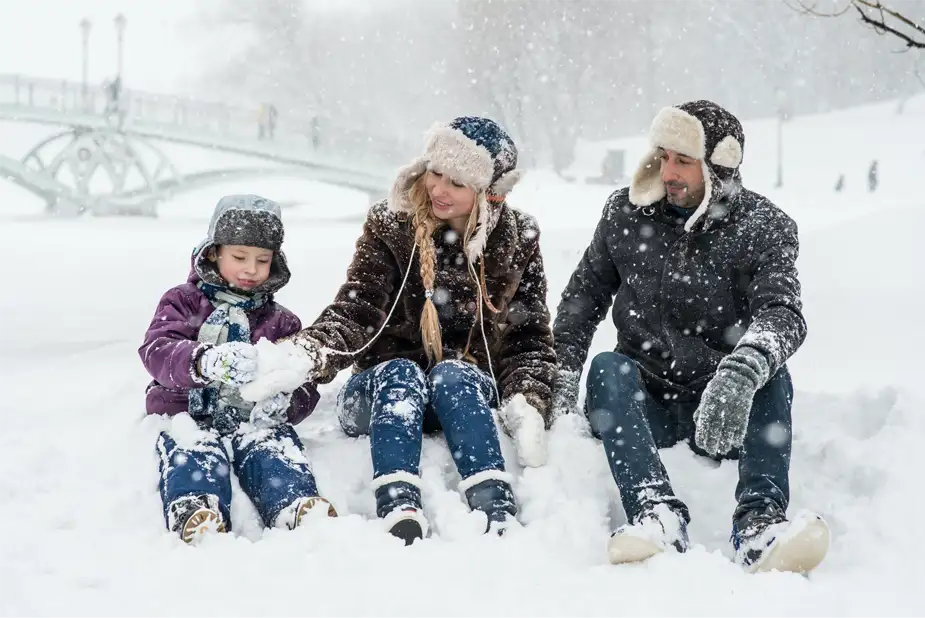 Glad familj sitter ute i snön med sitt barn