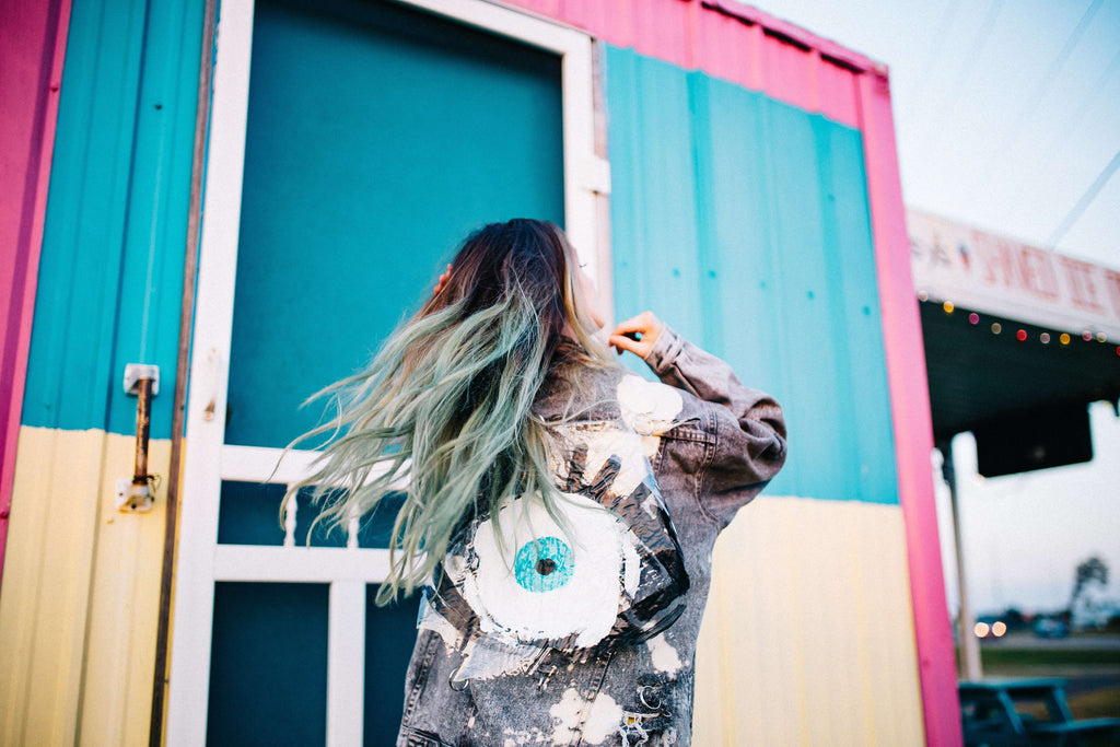 woman with dyed hair standing in front of vibrantly colored building