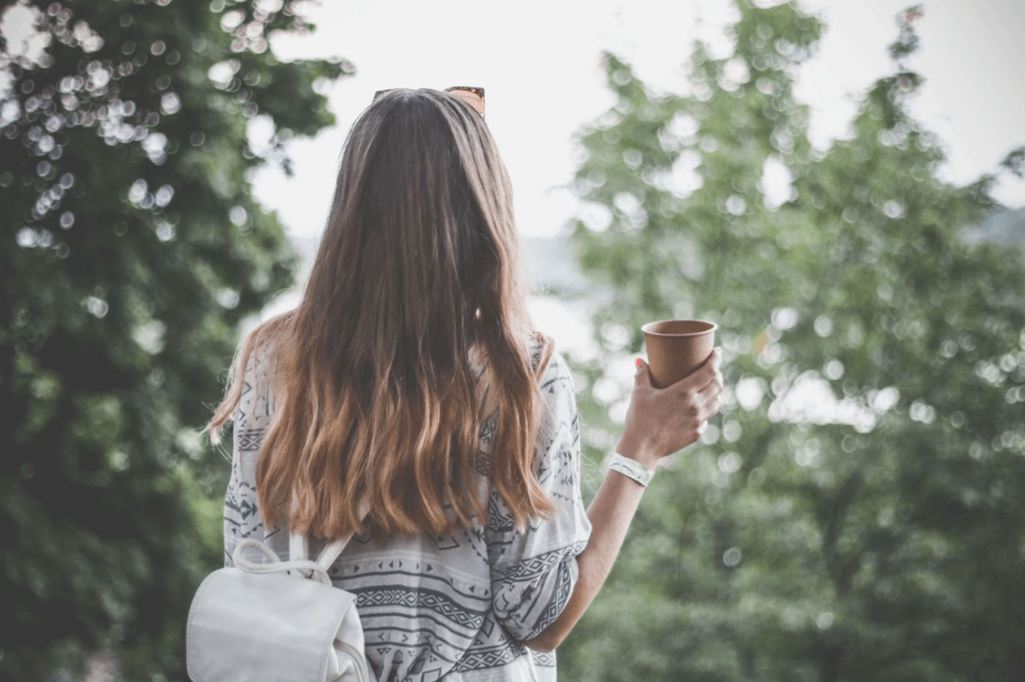 woman with long wavy hair holding coffee cup