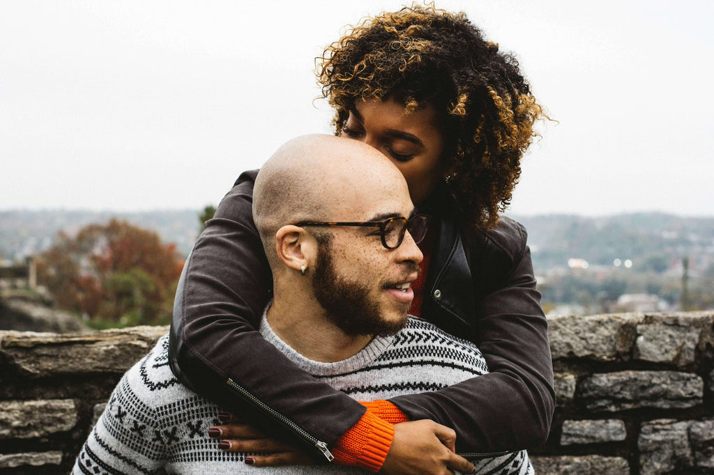 curly haired woman hugging man from behind