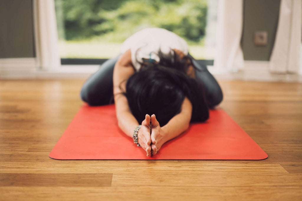 woman holding yoga pose on a mat on living room floor