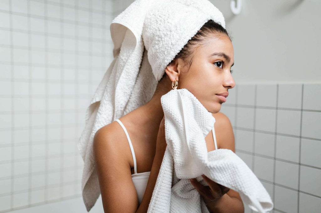 woman looking at skin in mirror after shower