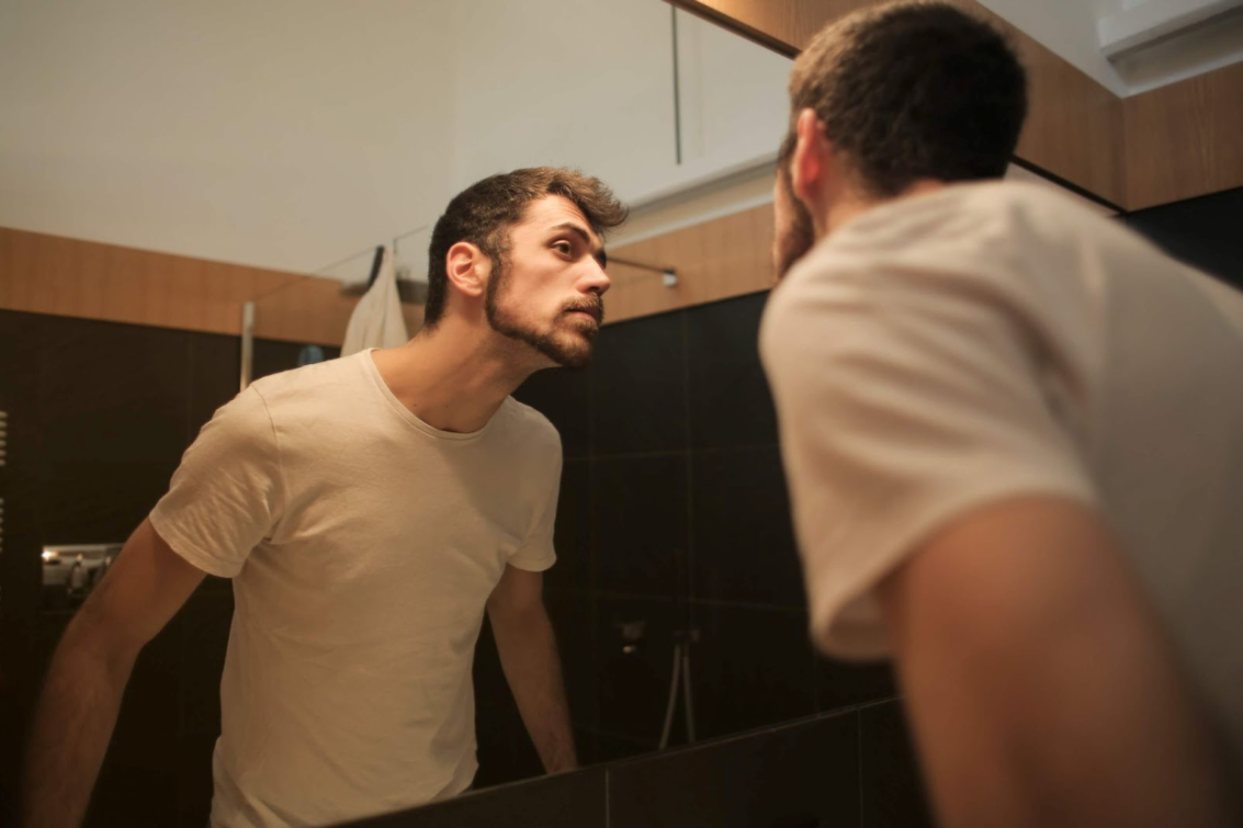 man examining skin in mirror