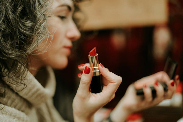 Woman holding and wearing red lipstick