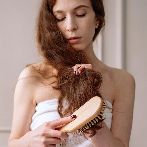 Biotin und Haarvitamine: Frau beim Haarekämmen