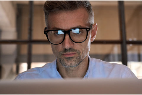 homem usando óculos de descanso preto frente ao computador