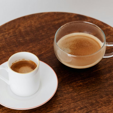 A shot of espresso next to a cup of coffee.