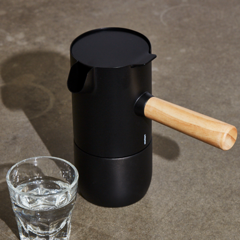 portable espresso machine next to glass of water