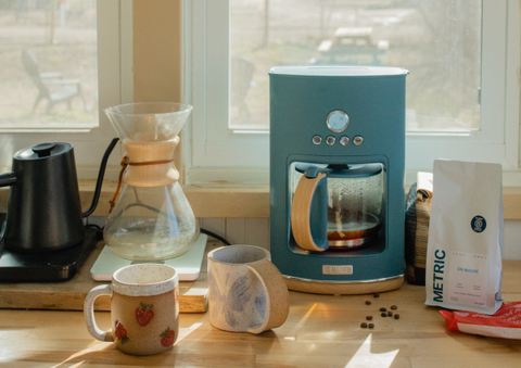 A home coffee set up made up of a coffee pot and chemex placed in front of a bright window.