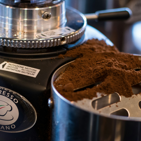 Ground coffee spilled from an espresso grinder.