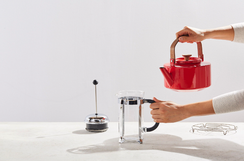 Preparing to warm the French Press with water from a red kettle.