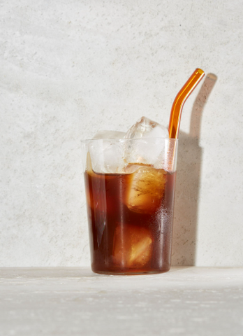 Glass of iced coffee with an orange straw.