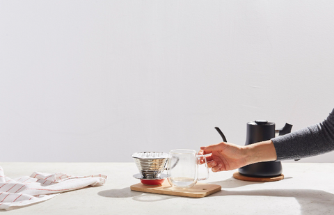 Hand reaching for Pour Over equipment on top of a scale.