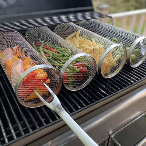 Four stainless steel BBQ grill baskets. The grill baskets are filled with vegetables and are on the BBQ.