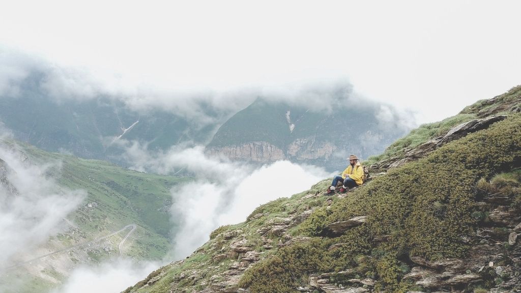 Homme trek assis sur le versant d'une montagne qui scrupte le paysage