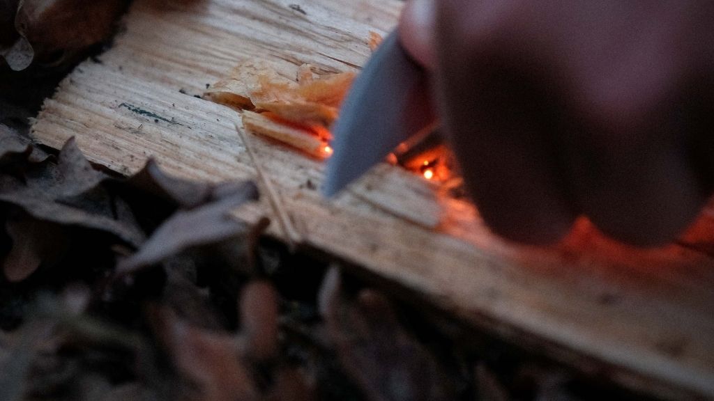 Allumage feu de bois en pleine nature, zoom sur les mains en utilisation de la pierre main. 