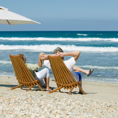 couple-sitting-on-deck-chairs-on-beach