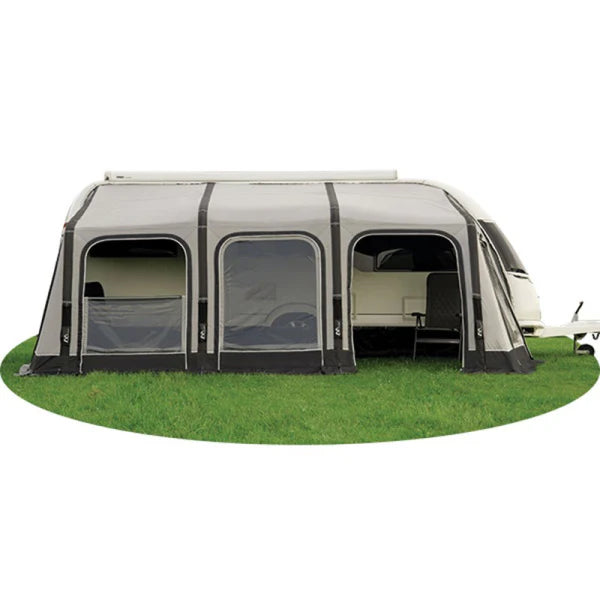 Caravan awning with arched windows attached to a caravan on a grassy field with cloudy sky in the background.
