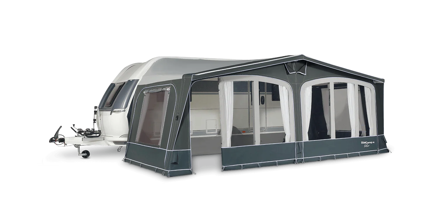 Grey and white caravan awning with arched windows and curtains attached to a white caravan on a transparent background.