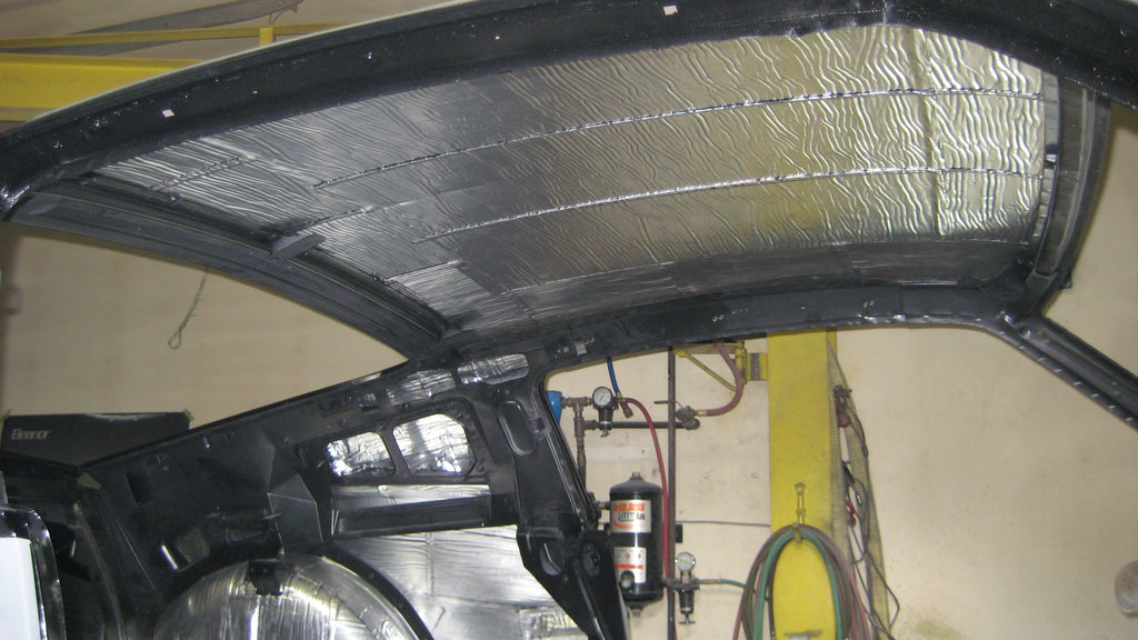 A Ford Mustang GT in the midst of a B-Quiet Sound Deadening upgrade. The vehicle's hood is open, exposing the engine bay prepared for soundproofing, while the interior is ready for the installation of B-Quiet's noise-reducing materials. The car is set against a backdrop of a busy garage, indicating an active sound deadening project. This setting exemplifies the practical application of B-Quiet's sound deadening solutions, designed for car enthusiasts looking to enhance their vehicle's acoustic comfort.