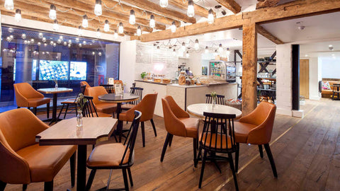 photo of the inside of a cafe with cakes on display and a mixture of furniture in the foreground