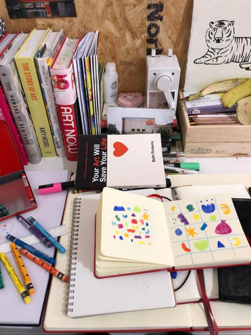 messy table with sketchbooks and pencil sharpener
