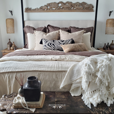 Image of a bed adorned with faux fur throws, chunky knit blankets, and velvet pillows.