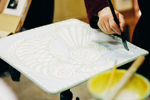 Juliet Swift painting the famous Bird Bites Fish motif