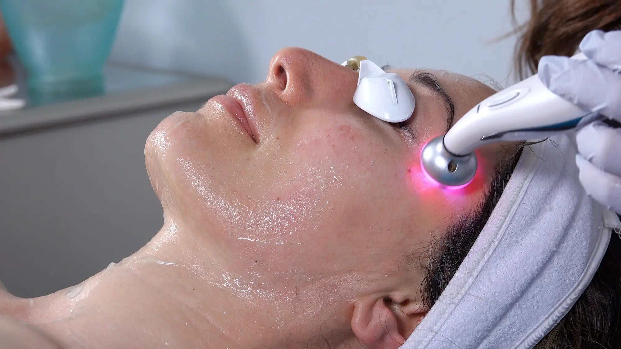 esthetician applying led light therapy to woman's skin