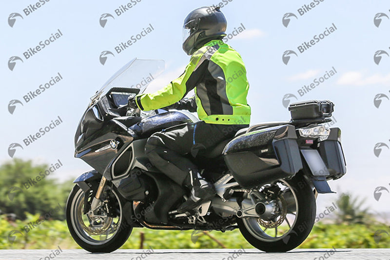 Motocyklista na czarnym motocyklu marki BMW w żółto czarnej kurtce