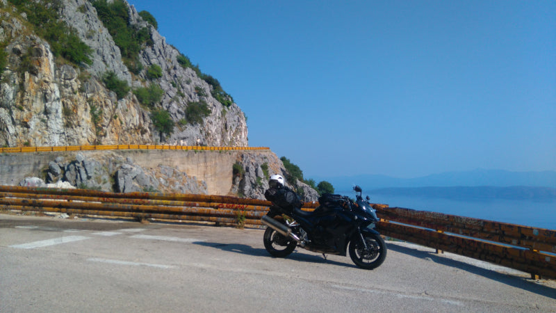 Motocykl stojący na chorwackiej serpentynie, piękny słoneczny dzień, a w tle chorwackie skały