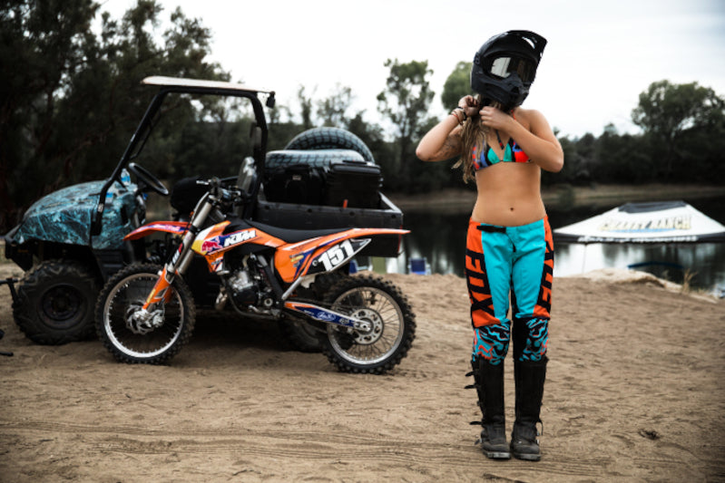 motocyklistka zapina kask ubrana w spodnie Fox Lady 180 w tle motocykl